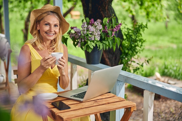 Vista frontale di una bella signora sorridente con una tazza di tè in posa per la telecamera