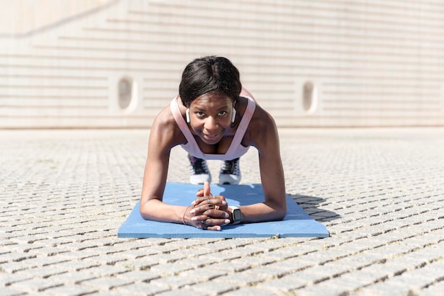 Vista frontale di una donna afroamericana che si allena all'aperto facendo un perfetto esercizio di plancia Concetto di motivazione di resistenza Attività sportiva sanitaria