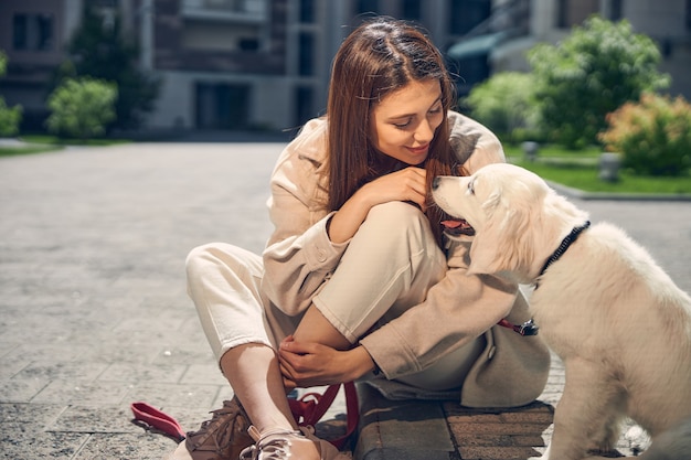 Vista frontale di una felice signora caucasica dai capelli lunghi seduta a gambe incrociate accanto al suo simpatico cane