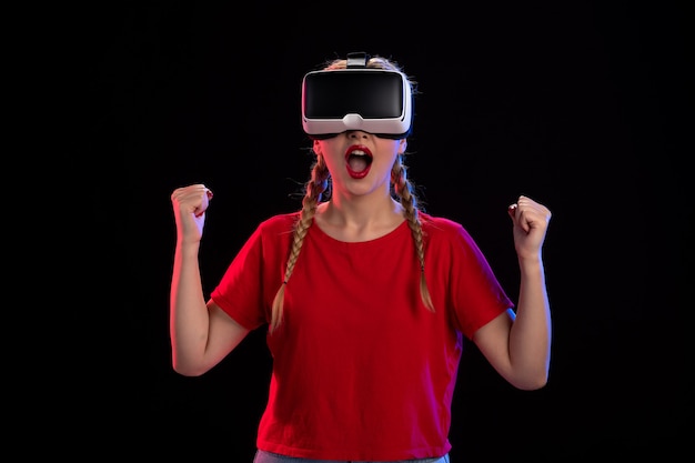 Vista frontale di una giovane donna che gioca con la realtà virtuale su un gioco visivo ad ultrasuoni scuro