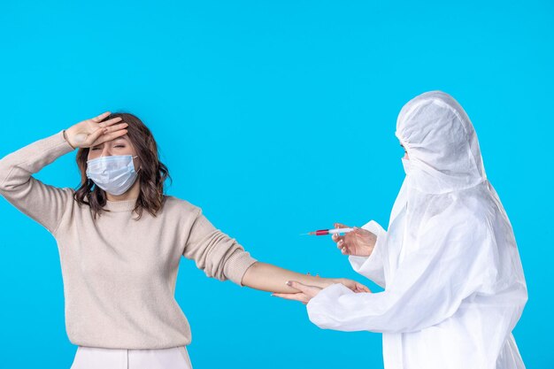 vista frontale dottoressa che prepara l'iniezione per il paziente sullo sfondo blu isolamento del virus medico covid- scienza salute pandemia malattia