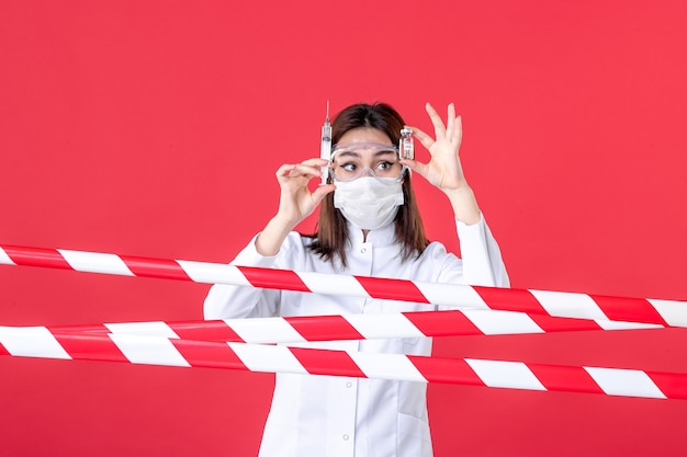 vista frontale dottoressa che prepara l'iniezione su sfondo rosso sigillato isolamento medico virus sanitario ospedaliero linea covid