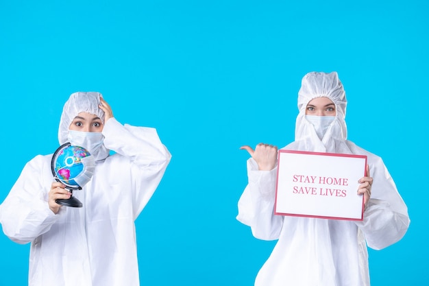 vista frontale dottoressa in tuta protettiva e maschera con nota di avvertimento su sfondo blu scienza della salute isolamento medico pandemico covid