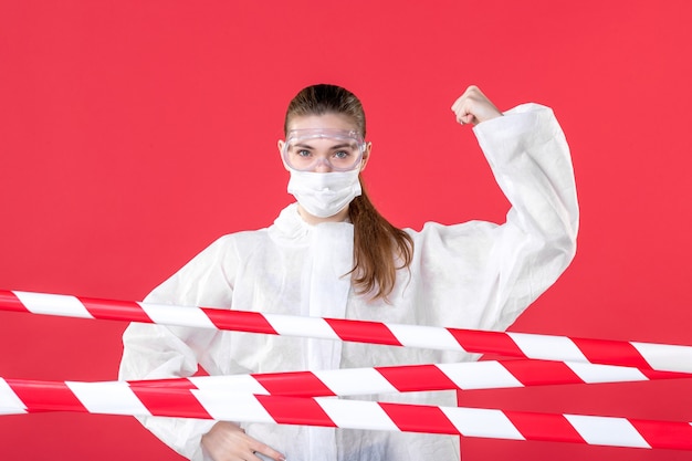 vista frontale dottoressa in tuta protettiva e maschera su sfondo rosso infermiera dei tessuti ospedalieri covid- maschera per la salute cura l'emozione del virus