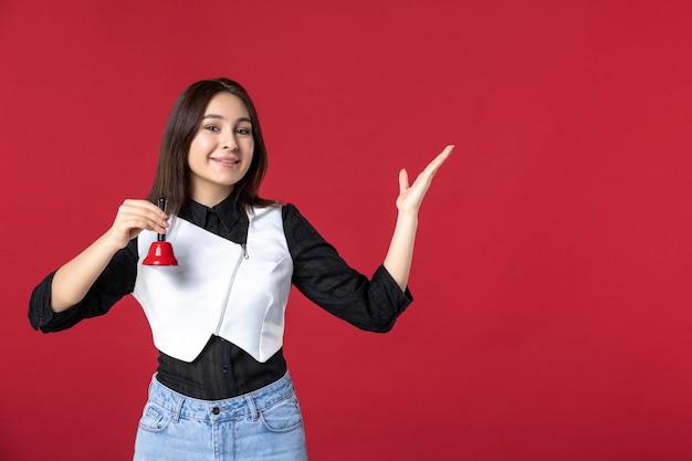 vista frontale giovane cameriera in uniforme con campanella su sfondo rosso donna cena lavoro sera lavoro ristorante lavoratore