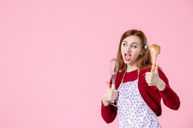 vista frontale giovane casalinga con cucchiaio e frusta su sfondo rosa colore cottura torta cucina cucina pasta dolce cibo torta