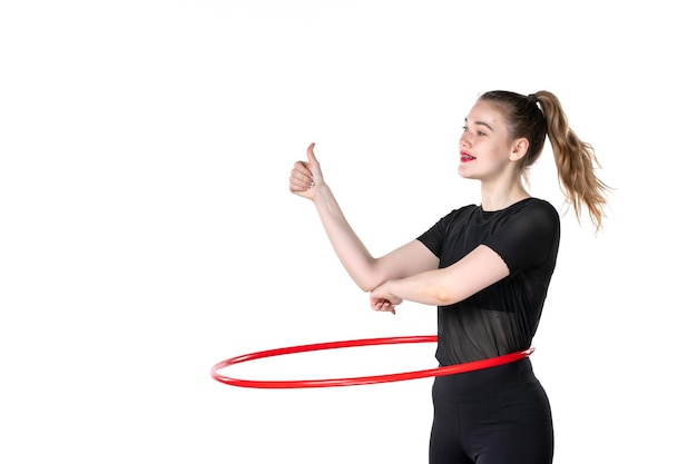vista frontale giovane donna che lavora con hula hoop rosso su sfondo bianco colore stile di vita donna salute corpo yoga sport atleta