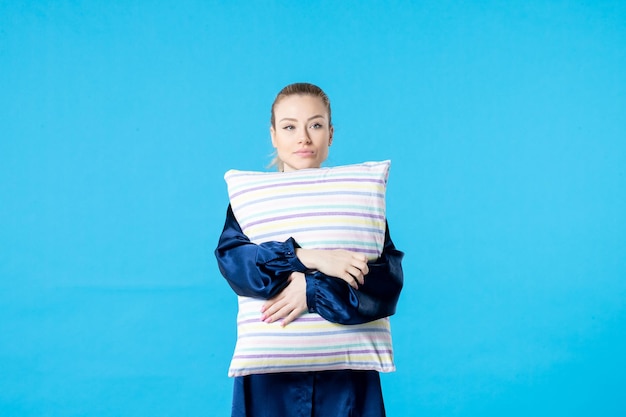 vista frontale giovane donna in pigiama che tiene cuscino su sfondo blu colore sonno incubo festa sogno sbadiglio notte stanco riposo letto
