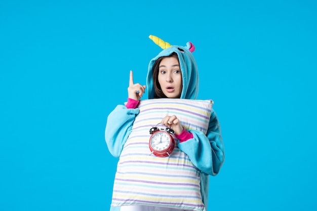 vista frontale giovane donna in pigiama party con cuscino e orologi su sfondo blu sogno sonno riposo incubo divertimento letto a tarda notte di gioco