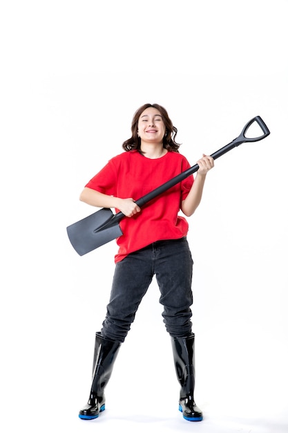 Vista frontale giovane femmina azienda pala nera come chitarra su sfondo bianco suolo di lavoro cimitero di terra di scavo emozione lavoro band musicale group