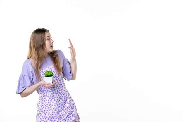 vista frontale giovane femmina che tiene piccola pianta verde su sfondo bianco pianta a foglia lavoro verde pianta d'appartamento donna fiore erba