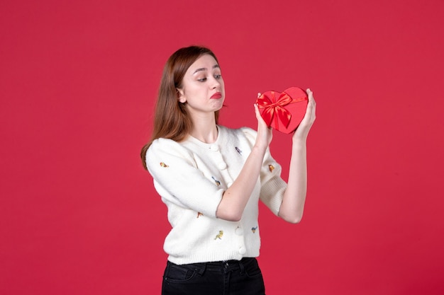 vista frontale giovane femmina che tiene rosso a forma di cuore presente su sfondo rosso giorno delle donne centro commerciale uguaglianza femminile moda sensuale