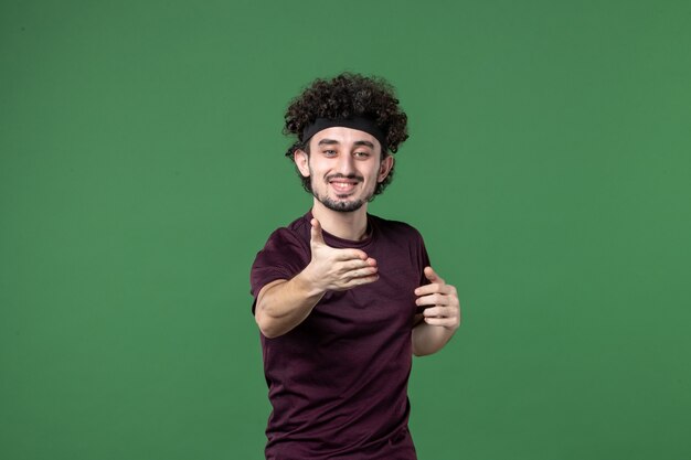 vista frontale giovane maschio cercando di stringere la mano su sfondo verde colore sport palestra allenamento in esecuzione modello di salute emozione atleta