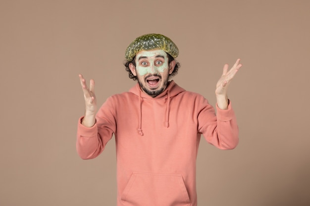 vista frontale giovane maschio con berretto bouffant e maschera sul viso su sfondo marrone terapia per la cura della pelle dei capelli salone della pelle per il viso