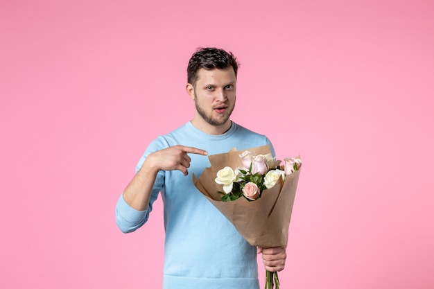 vista frontale giovane maschio con bouquet di bellissimi fiori su sfondo rosa parco divertimenti giorno delle donne sensuali marzo appuntamento femminile matrimonio uguaglianza amante