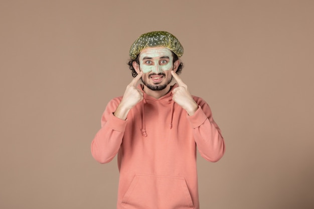 vista frontale giovane maschio con cappuccio bouffant su sfondo marrone salone per la cura della pelle terapia della pelle massaggio termale facciale