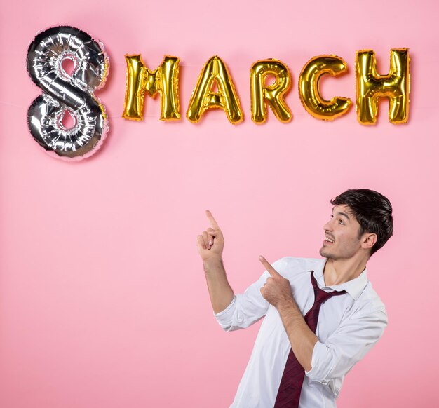 Vista frontale giovane maschio con decorazione di marzo su sfondo rosa colore presente uguaglianza matrimonio femminile festa della festa della donna