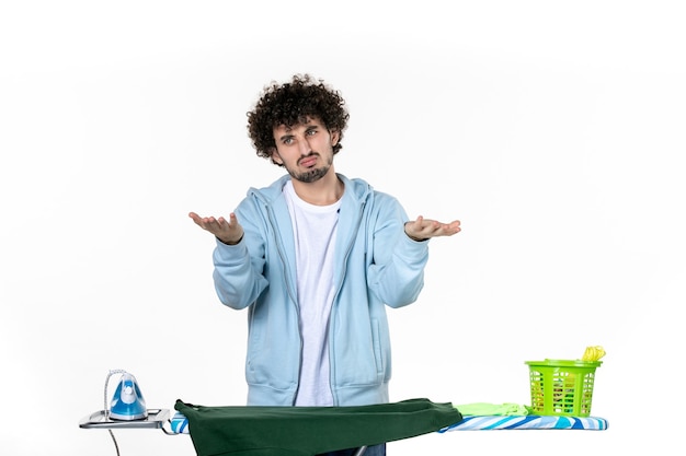 vista frontale giovane maschio dietro l'asse da stiro su sfondo bianco lavori domestici stiratura colore vestiti lavanderia emozione man