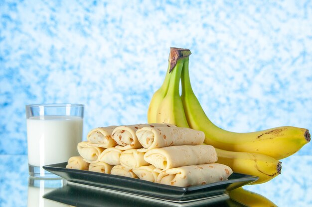 vista frontale gustose frittelle arrotolate con banane e latte su sfondo chiaro zucchero da dessert mattina frutta colore torta al latte
