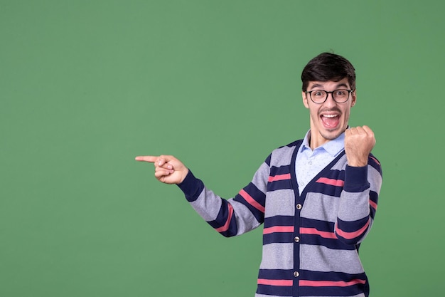 vista frontale insegnante maschio che indica da parte con espressione eccitata su sfondo verde college donna lezione biblioteca studente università scuola lavoro libri