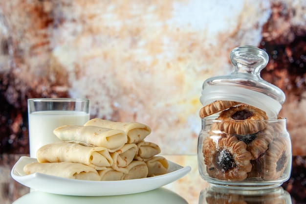 Vista frontale laminati frittelle dolci con latte e biscotti su sfondo marrone chiaro farina di fiori torta colazione colore mattina torta zucchero cibo