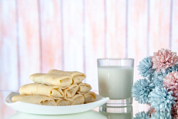 Vista frontale laminati frittelle dolci con un bicchiere di latte sullo sfondo chiaro pasto colazione cibo zucchero fiore colore torta mattina