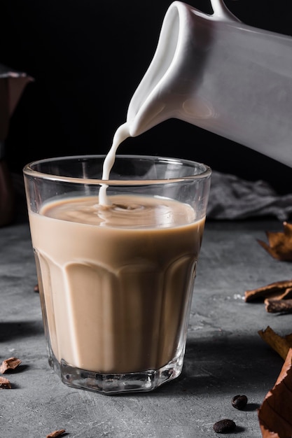 Vista frontale latte che viene versato nel bicchiere di caffè