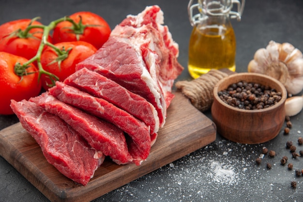 vista frontale ravvicinata carne fresca affettata carne cruda con pomodori rossi su superficie scura