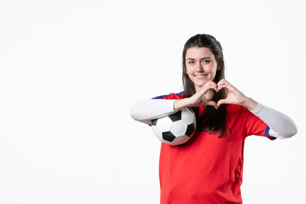 Vista frontale sorridente giovane femmina in abiti sportivi con pallone da calcio