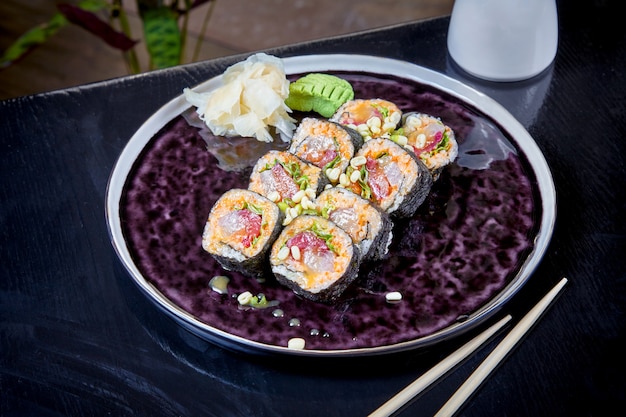 Vista frontale su rotolo piccante con tonno orsalmon. Suchi. stile di cibo giapponese. Frutti di mare. Pasto sano, equilibrato e dietetico. involtini di sushi sul piatto scuro. Copia spazio, sfondo di cibo.