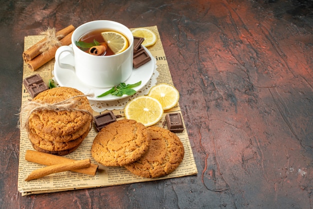 vista frontale tazza di tè con limoni gialli freschi e biscotti su sfondo scuro mattina dolce cerimonia di colore tè frutta