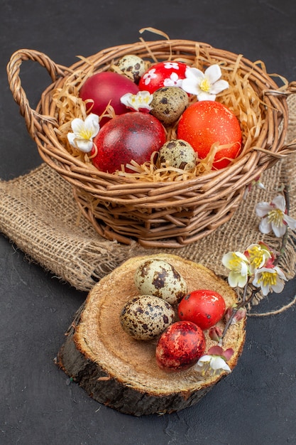 vista frontale uova di pasqua colorate all'interno del cesto su superficie scura