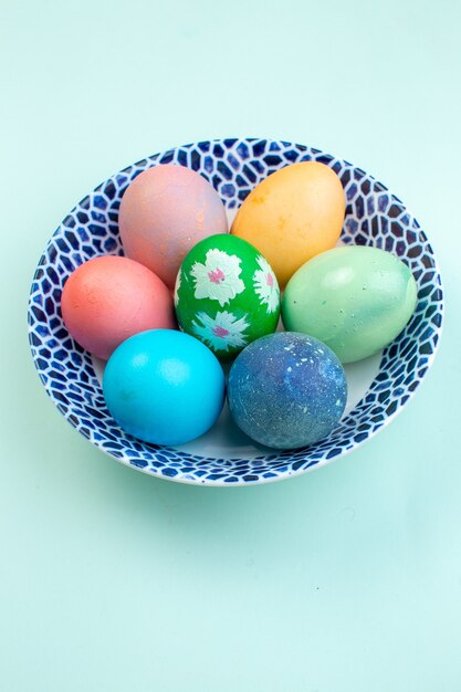 Vista frontale uova di pasqua colorate all'interno della piastra sulla superficie blu ornati a molla multi vacanze colorate colori etnici pasqua