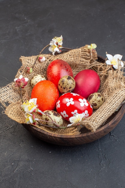 vista frontale uova di pasqua colorate all'interno della piastra sulla superficie scura colore vacanza ornato concetto uccello primavera pasqua