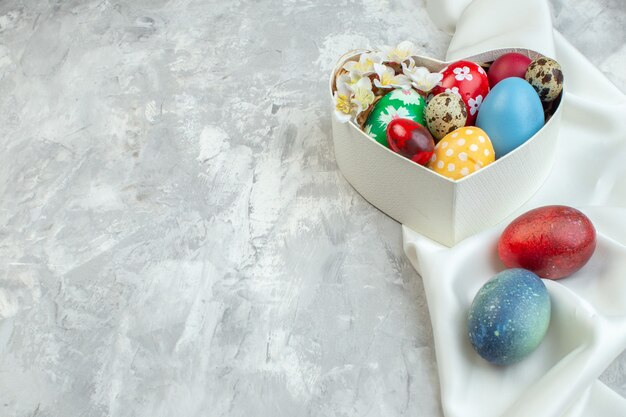 vista frontale uova di pasqua colorate all'interno della scatola a forma di cuore su sfondo bianco concetto di femminilità ornato colorato primavera pasqua
