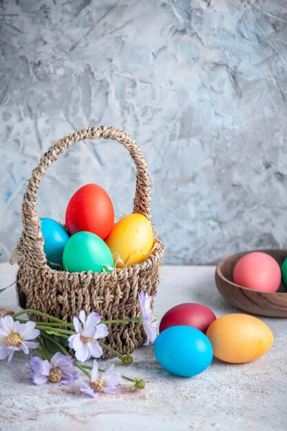 vista frontale uova di pasqua colorate all'interno di un bellissimo cesto su superficie bianca