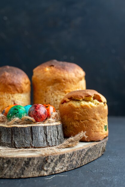 vista frontale uova di pasqua colorate con gustose torte al forno su sfondo blu scuro colore colorato ornato vacanza pasqua