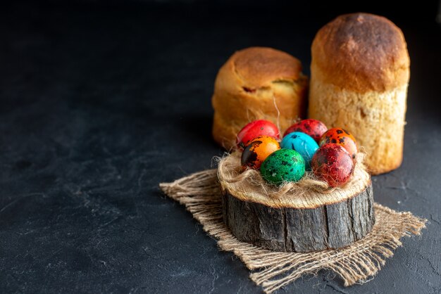 vista frontale uova di pasqua colorate su un pezzo di legno sfondo scuro colore etnico ornato colorato holiday