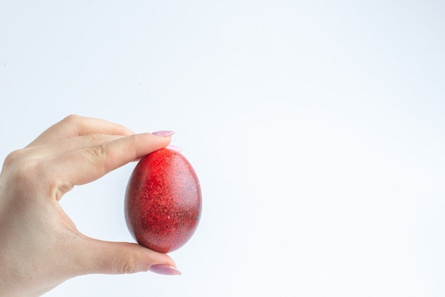 vista frontale uova dipinte di rosso in mani femminili su sfondo bianco primavera colorato novruz concetto di vacanza ornato
