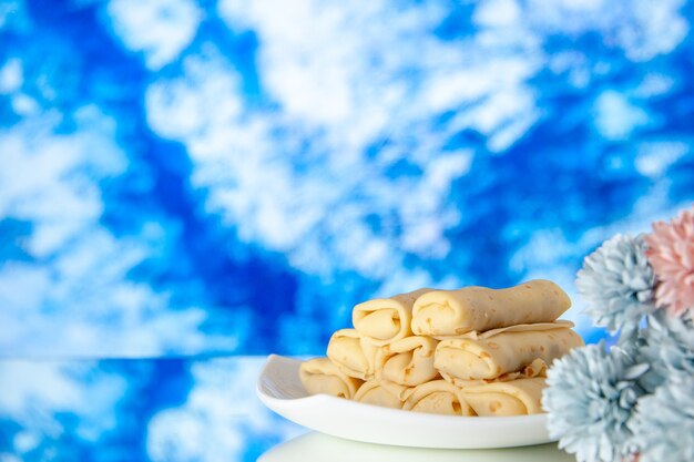 Vista frontale Yummy frittelle arrotolate su sfondo azzurro colazione torta zucchero dessert pasto mattina dolce colore cookie