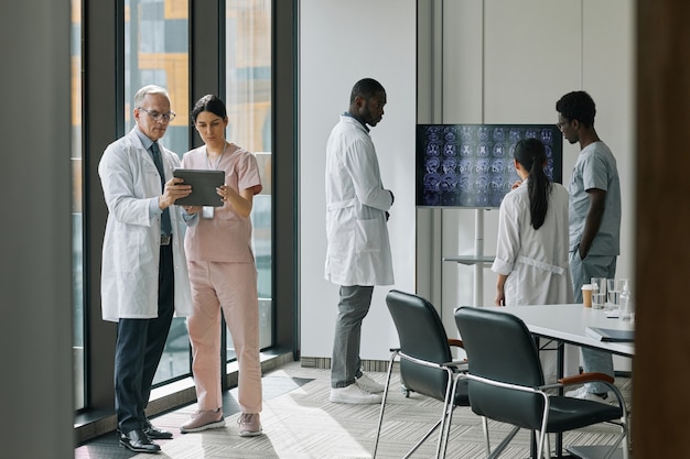 Vista grandangolare a diversi gruppi di medici in sala conferenze, spazio copia