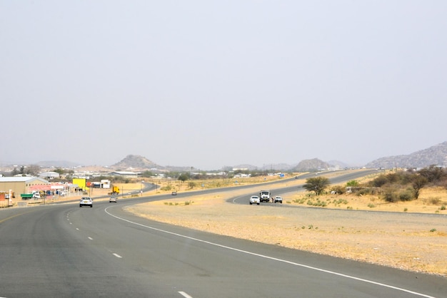 Vista in auto di una strada di asfalto tortuosa nel deserto in prospettiva con le auto che guidano avanti