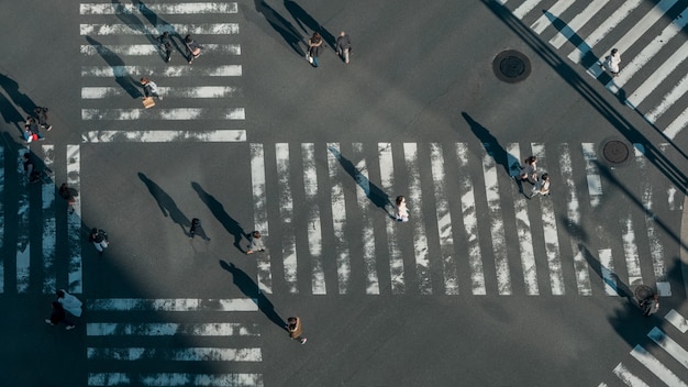 Vista in elevazione su una folla di attraversamenti pedonali giapponesi nell'intersezione stradale con la luce di un tramonto. Vista aerea di persone asiatiche in attraversamento pedonale scramble occupato del Giappone.