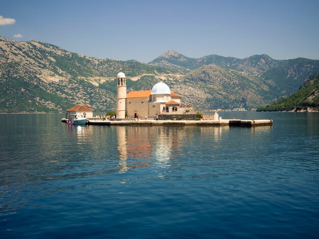 Vista in lontananza l'isola e la chiesa di Nostra Signora della barriera corallina nella baia di Kotor in Montenegro