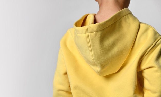 Vista ingrandita dalla parte posteriore del fuoco sul cappuccio del maglione giallo del ragazzo