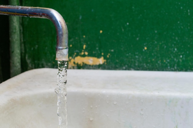 Vista ingrandita del vecchio rubinetto dell'acqua macchiato con messa a fuoco selettiva e sfocatura dello sfondo