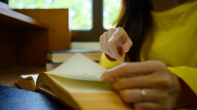 Vista ingrandita della donna studentesca che legge il libro di testo facendo ricerca e preparando l'esame Conoscenza dell'apprendimento dell'istruzione e università