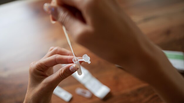 Vista ingrandita della mano femminile che posiziona il tampone per campioni di coronavirus in una soluzione salina.