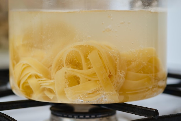 Vista ingrandita delle fettuccine in acqua bollente in una pentola di vetro trasparente