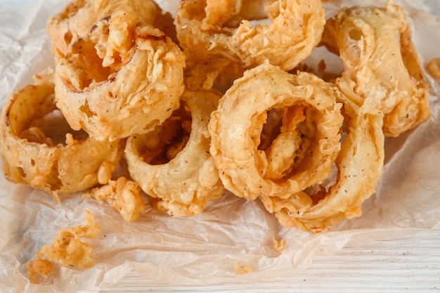 Vista ingrandita di deliziosi anelli di calamari fritti freschi su carta bianca. Frutti di mare, cucina giapponese, fast food, spuntino appetitoso per la birra.